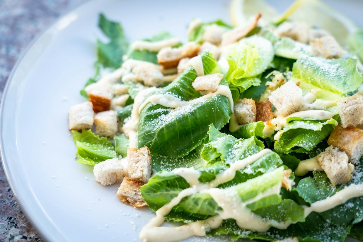 Tigela de salada caesar com alface romana fresca, fatias de peito de frango grelhado, croutons dourados e queijo parmesão em lascas