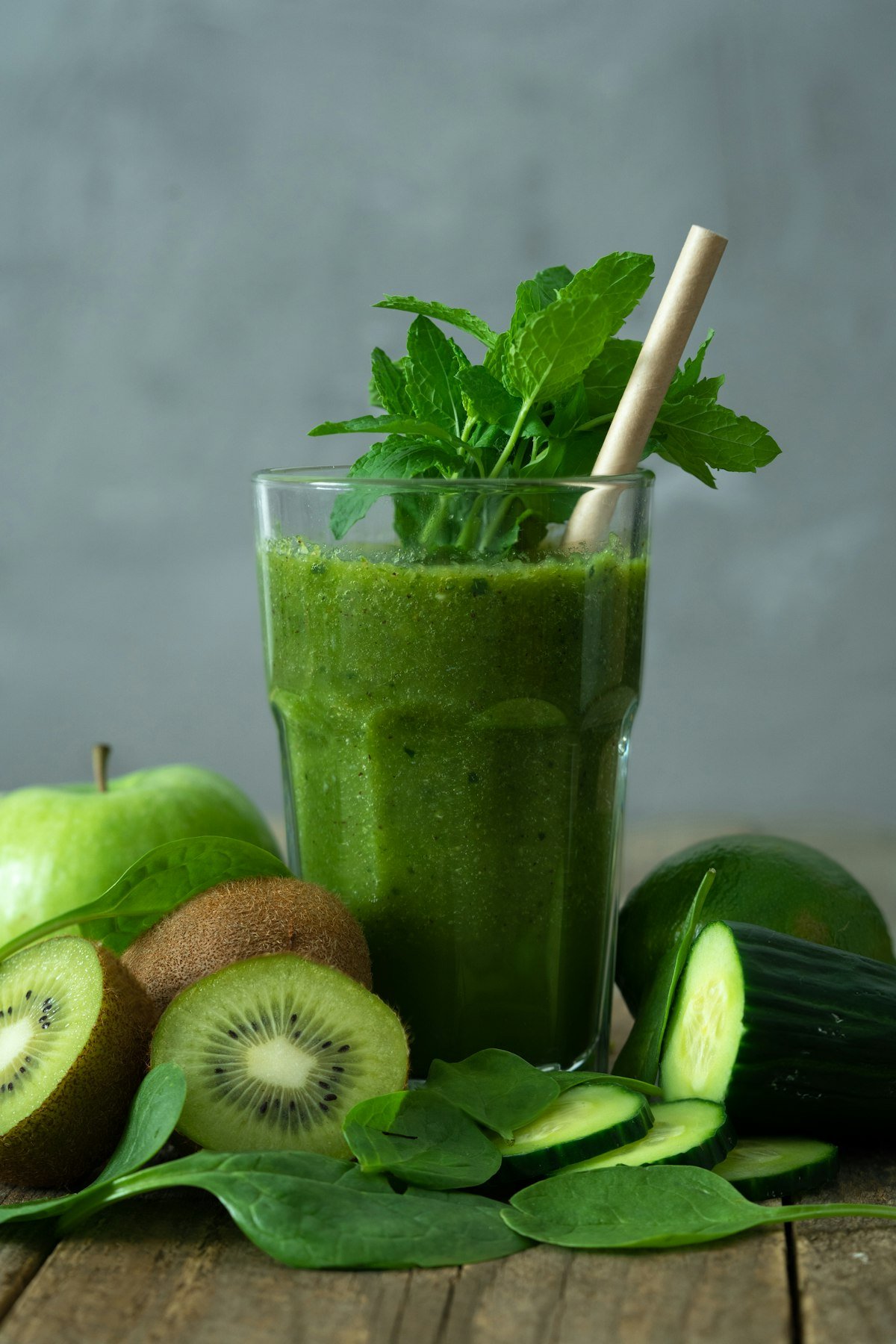 Copo de vidro alto com suco verde detox refrescante com gelo e fatia de limão na borda